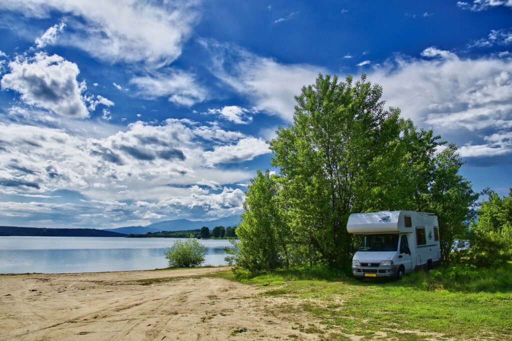 Ein Wohnmobil parkt unter einem Baum. Man muss sich aber nicht verstecken, wenn manals Camper  im Wohnwagen oder Wohnmobil Camping betreibt.