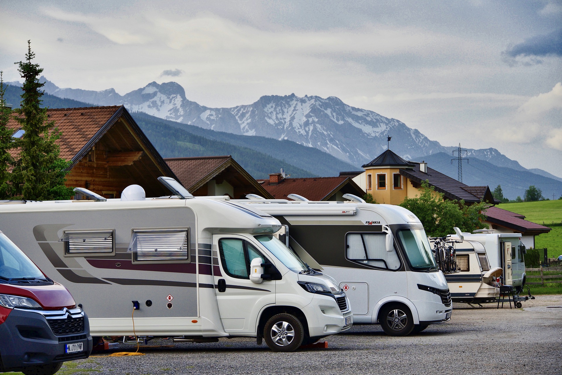 Verschiedene Wohnmobile und Wohnwagen parken vor einer Bergkulisse