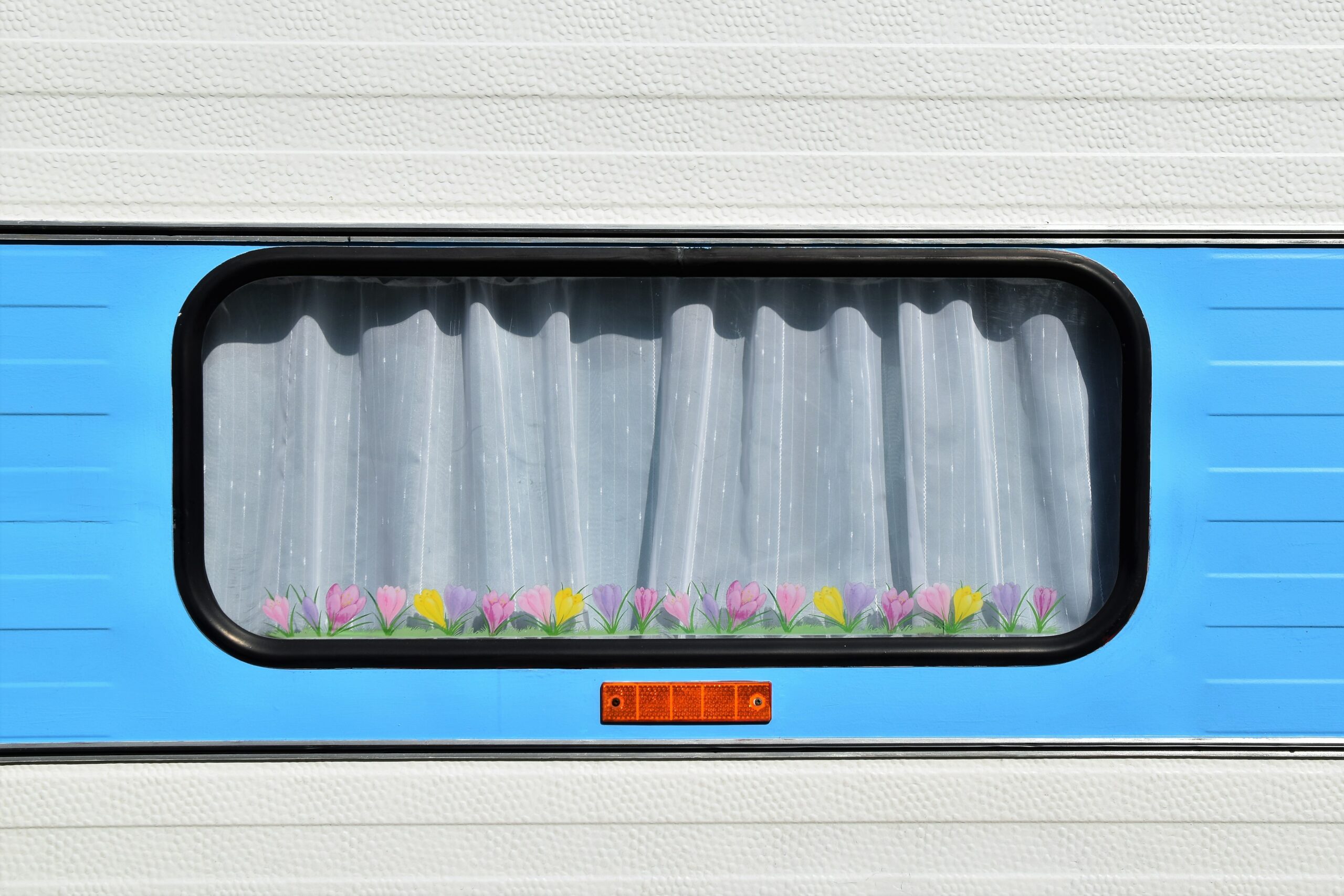 Nahaufnahme eines Wohnwagenfensters mit Vorhang