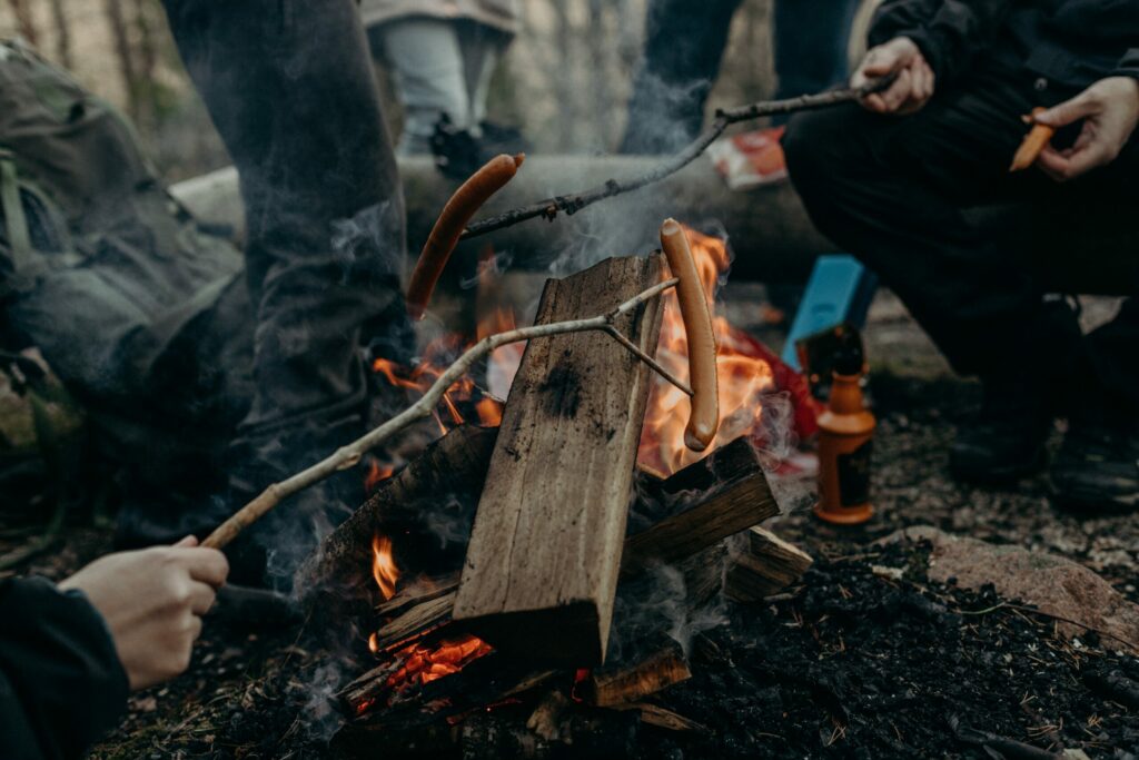 Würstchen über dem Lagerfeuer braten ist eine weitere gute Idee, wie man Jugendliche für Campingurlaub begeistern kann.